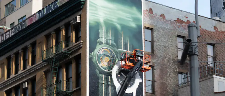 Two workers installing a large printed mural on a building facade